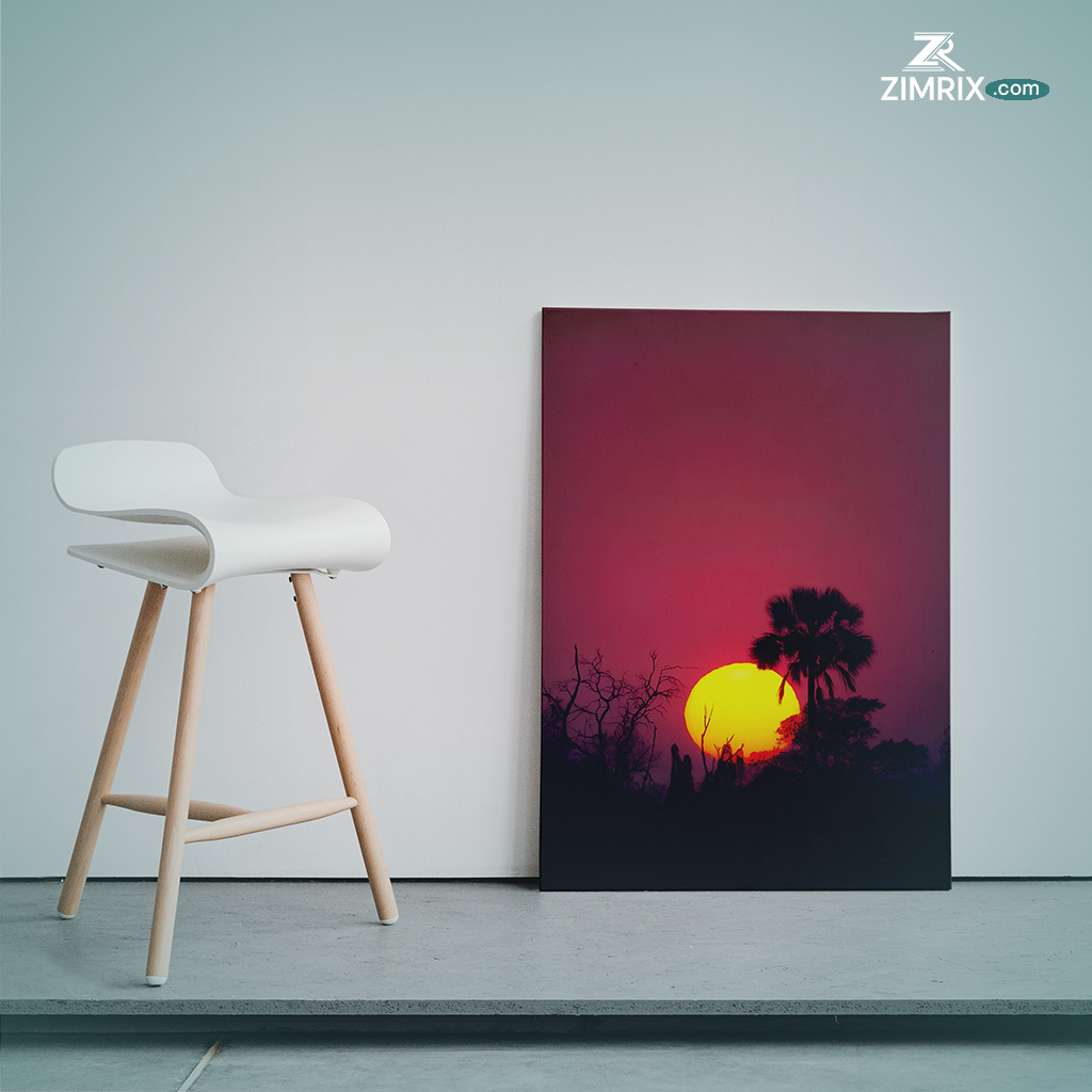 Sunset over a landscape with silhouetted trees and a palm tree, featuring a vibrant orange and pink sky.