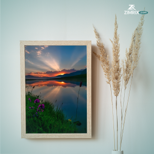 A serene sunset casts vibrant colors over a tranquil lake, surrounded by blooming flowers and lush green grass.