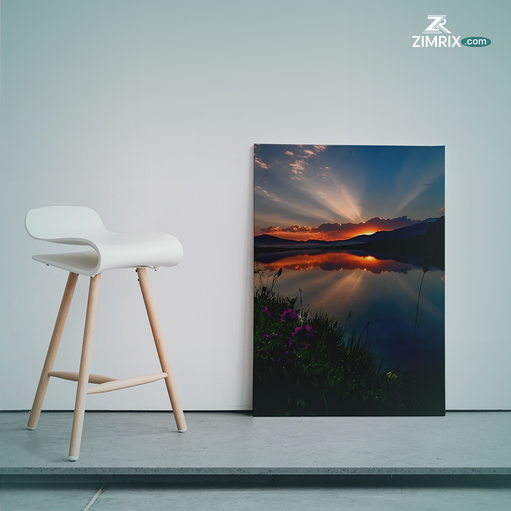 A serene sunset casts vibrant colors over a tranquil lake, surrounded by blooming flowers and lush green grass.