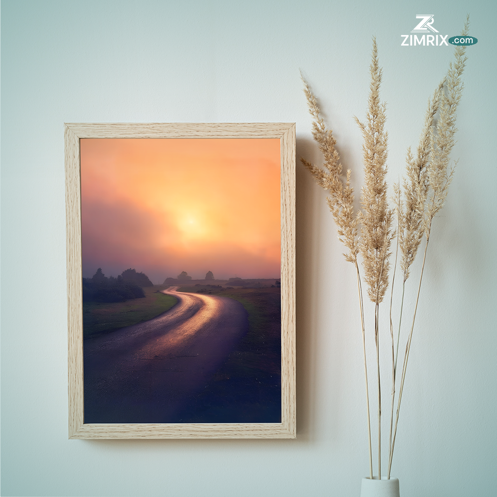 A distant road stretches towards a vibrant sunset, casting warm hues across the sky and illuminating the landscape.